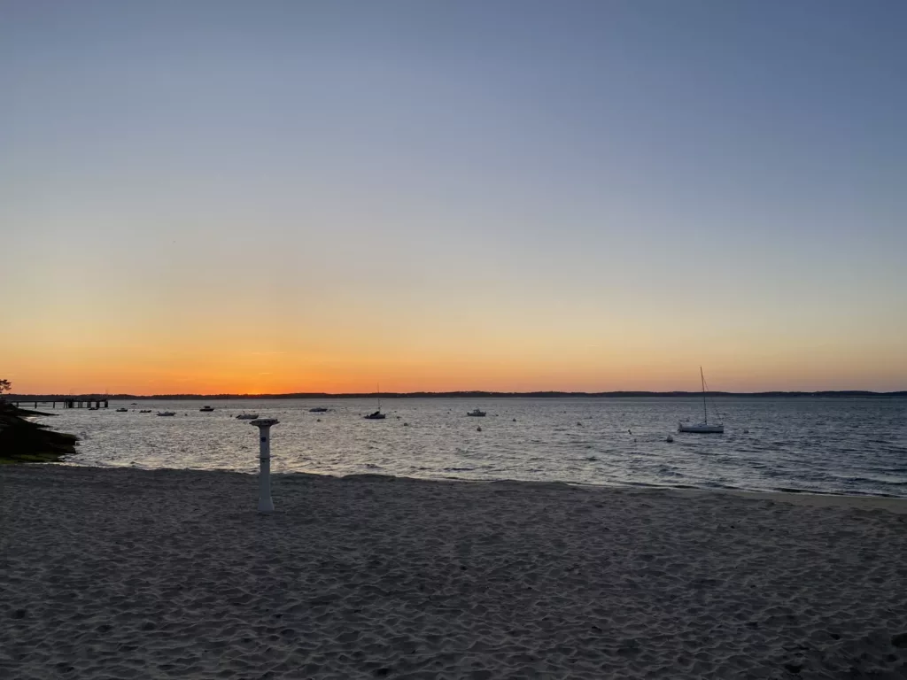 Vue sur le coucher de soleil du bassin d'Arcachon, avec en fond le bassin nord et au premier plan du sable, pour la page maintenance et refonte de site internet.